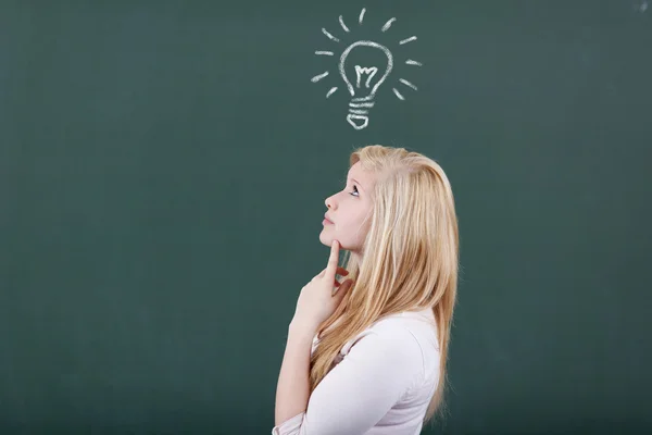 Girl Looking Up While Lightbulb Drawn On Chalkboard In Classroom — Stock Photo, Image