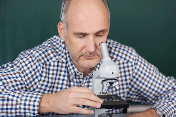 Professor op zoek via Microscoop in de wetenschap klasse — Stockfoto