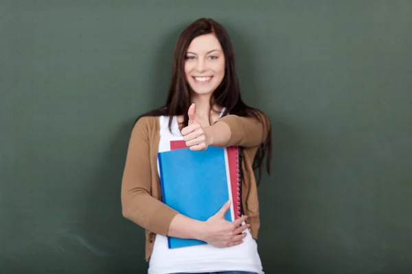Woman Holding Files While Showing Thumbsup Sign Against Chalkboa — Stock Photo, Image