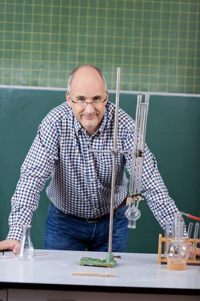 Professor confiante que se inclina na mesa na aula de ciências — Fotografia de Stock