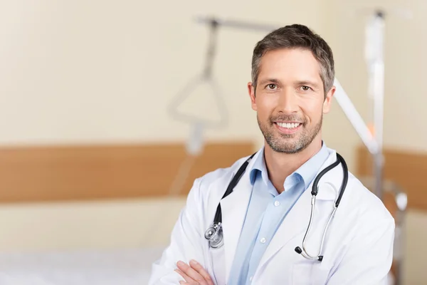 Улыбающийся доктор со скрещенными руками, стоящий в больнице — стоковое фото