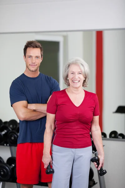 Szczęśliwy senior kobieta z jej trener na siłowni — Zdjęcie stockowe