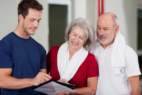 Instructor mostrando resultados de salud en portapapeles a pareja mayor — Foto de Stock