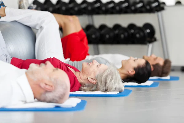 Family Exercising While Lying On Mat At Gym — Stock Photo, Image