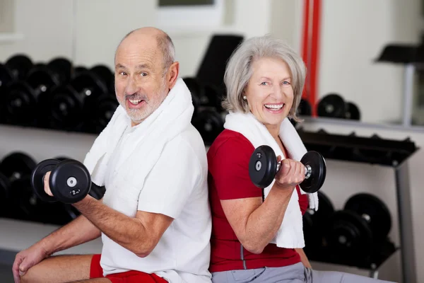 Pasangan Senior Angkat Dumbbells Ketika Duduk di Gym Stok Gambar Bebas Royalti