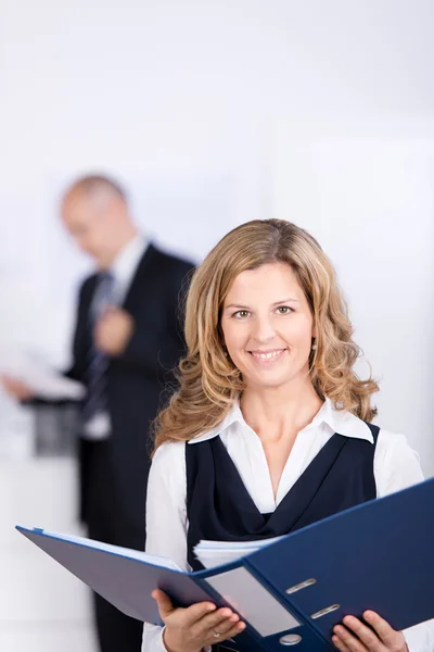 Empresária segurando Binder com colega de trabalho no fundo — Fotografia de Stock