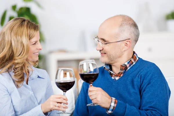 Pareja tostadas copas de vino tinto mientras se miran entre sí — Foto de Stock