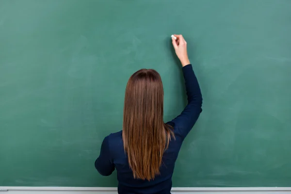 Woman writing on a blackboard — Stock Photo, Image