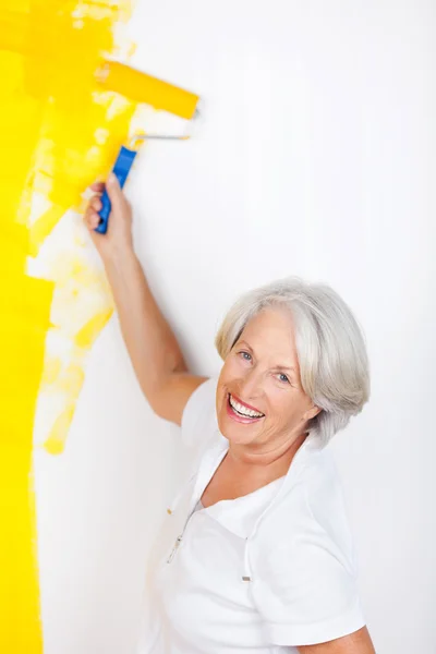 Parete di pittura della donna anziana con il rullo di vernice — Foto Stock