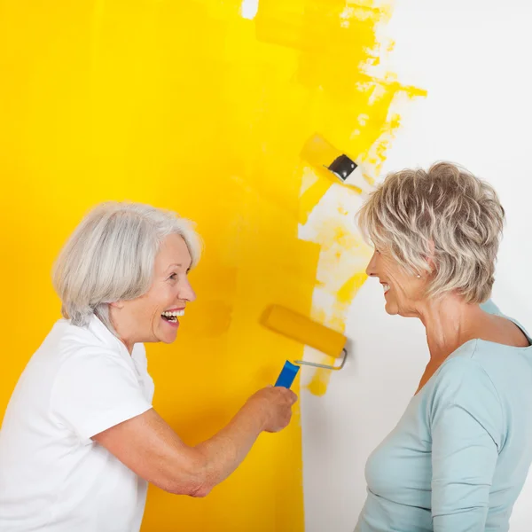 Seniorinnen bemalen Wand mit gelber Farbe — Stockfoto