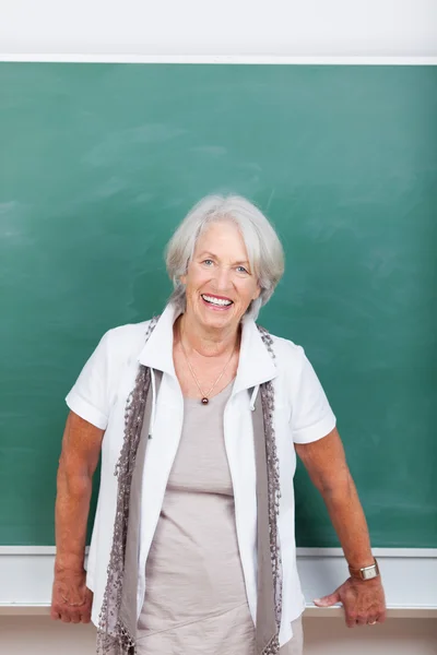 Leende senior kvinna framför en svart tavla — Stockfoto