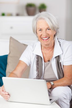 Senior Woman Using Laptop While Sitting On Sofa clipart