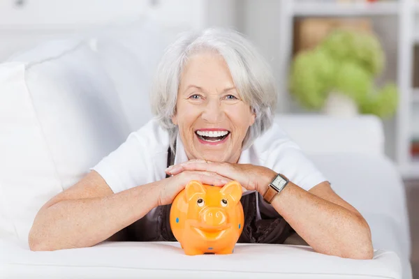 Mujer mayor con Piggybank acostada en un sofá —  Fotos de Stock