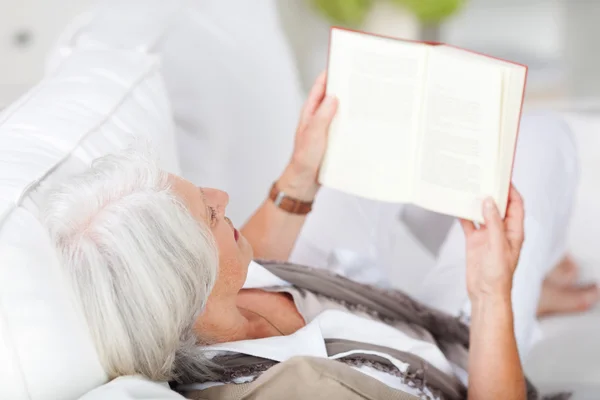 Mujer mayor relajándose mientras lee un libro — Foto de Stock