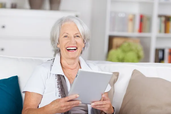 Skrattar vackra senior med en tablet-pc — Stockfoto