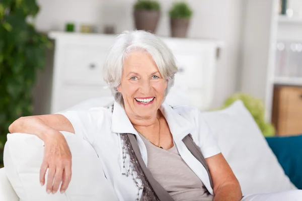 Пожилая женщина сидит на диване дома — стоковое фото