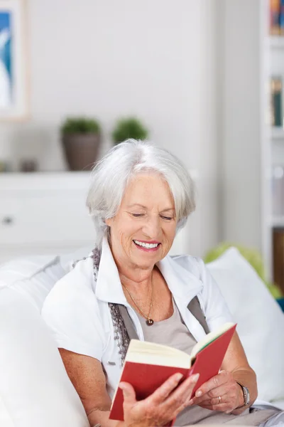 Пожилая женщина расслабляется и читает книгу — стоковое фото