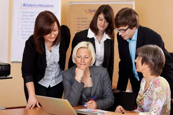 Business team gathered around a laptop — Stock Photo, Image