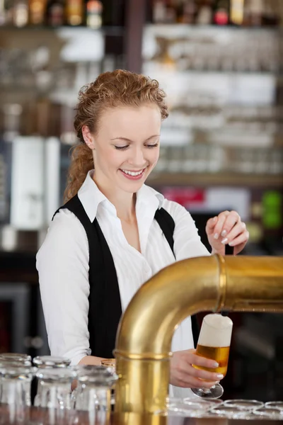 Fröhliche Bardame schenkt Bier vom Fass ein — Stockfoto