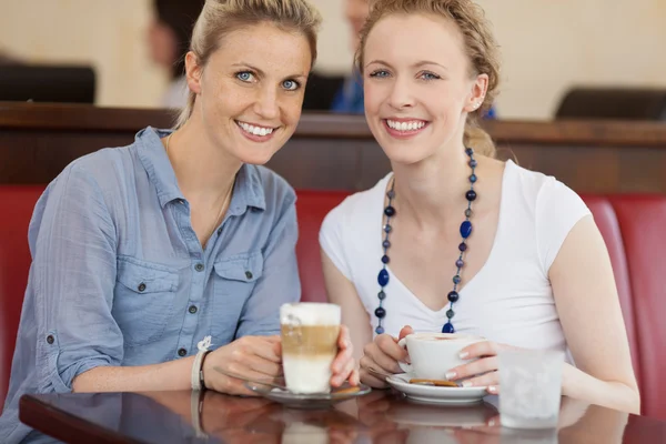 Two happy female friends enjoying a cup of cofee — Stock Photo, Image