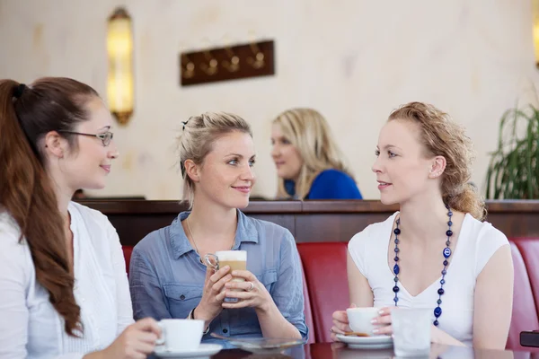Троє друзів п'ють каву в кафе — стокове фото