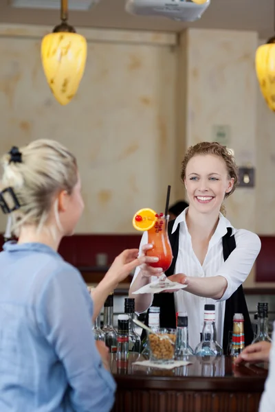 Kellnerin gibt einer Frau an einer Bar einen Cocktail — Stockfoto