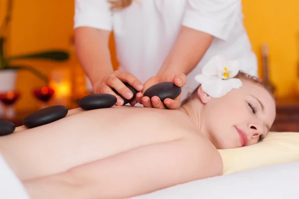 Jonge vrouw met een massage met hete stenen — Stockfoto