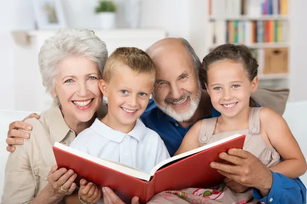 Пожилая пара читает своим внукам — стоковое фото