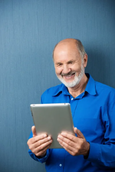 Homem idoso rindo de informações em seu tablet — Fotografia de Stock