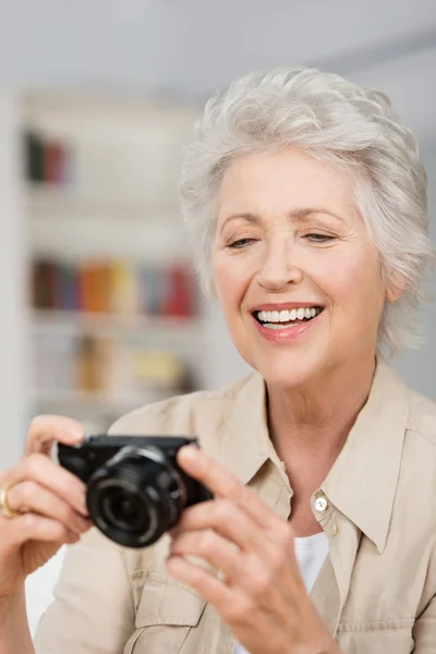 Happy senior woman setting her compact camera — Stock Photo, Image