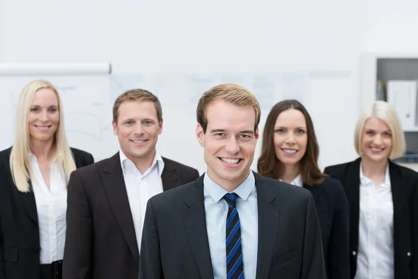 Handsom young manager with a happy team behind him — Stock Photo, Image