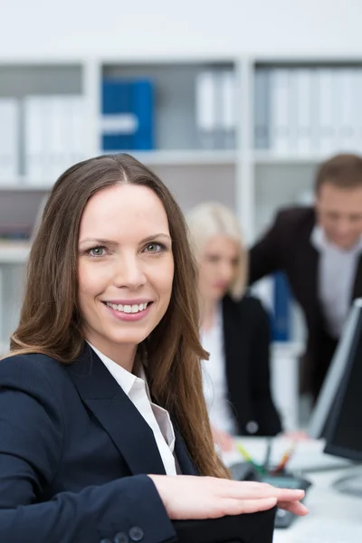 Üzletasszony egy forgalmas irodában mosolyogva — Stock Fotó