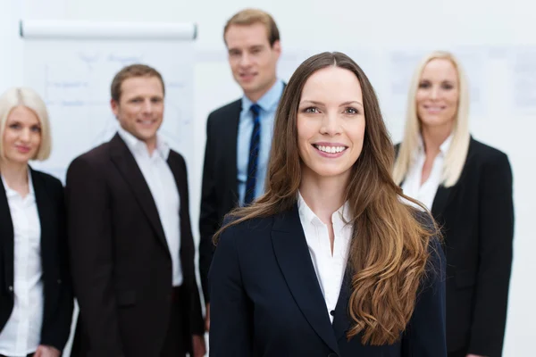 Zakenvrouw lachend met een team achter haar — Stockfoto