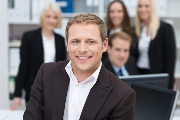 Selbstbewusster Geschäftsmann, der von seinem Team unterstützt wird — Stockfoto