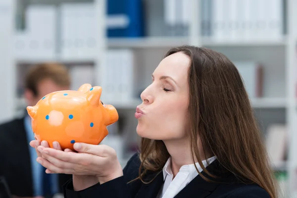 Geschäftsfrau küsst ihr Sparschwein — Stockfoto