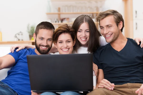 Groep vrienden lachen om een laptop — Stockfoto