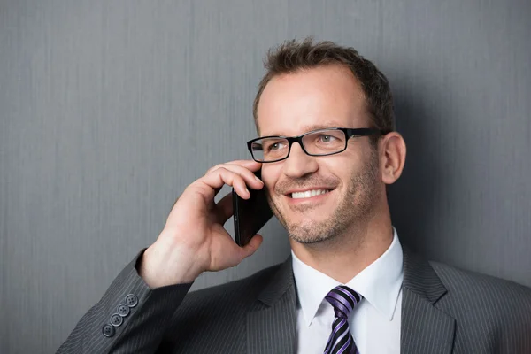 Hombre de negocios sonriente en el teléfono móvil — Foto de Stock