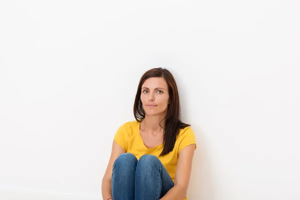 Жінка сидить у підлозі, спираючись на стіну — стокове фото