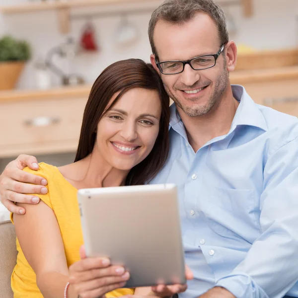 Счастливая пара улыбается и читает свой планшетный компьютер — стоковое фото