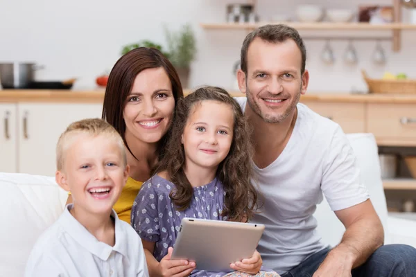 Jovem família feliz relaxante com um tablet-pc — Fotografia de Stock