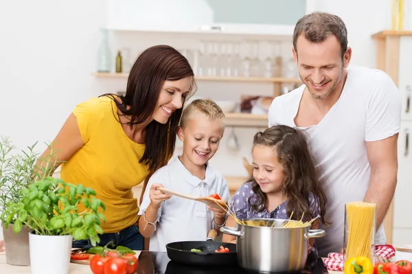 Ung familj matlagning i köket Stockfoto