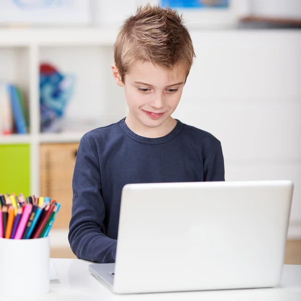 Yakışıklı genç çocuk bir dizüstü bilgisayar kullanarak — Stok fotoğraf