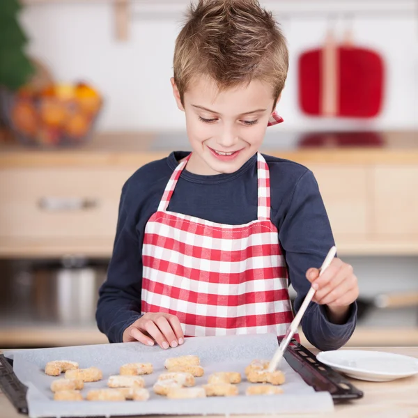 Happy little boy glazing cookies — Stock Photo, Image