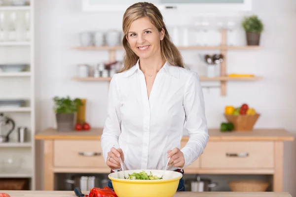 Lächelnde junge Hausfrau wirft einen Salat — Stockfoto