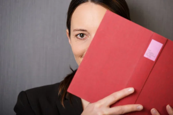Woman peeking out from behind a book — Stock Photo, Image