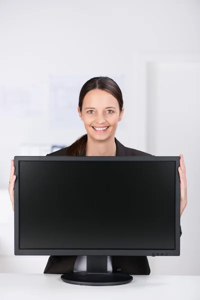 Mujer de negocios sonriente con un monitor de pantalla ancha —  Fotos de Stock