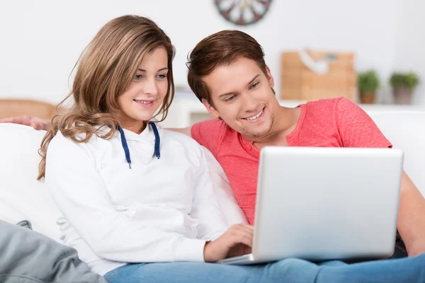Cariñosa pareja adolescente relajarse con un ordenador portátil — Foto de Stock