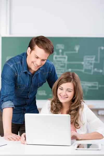 Young man helping a teenage girl in class — Stock Photo, Image