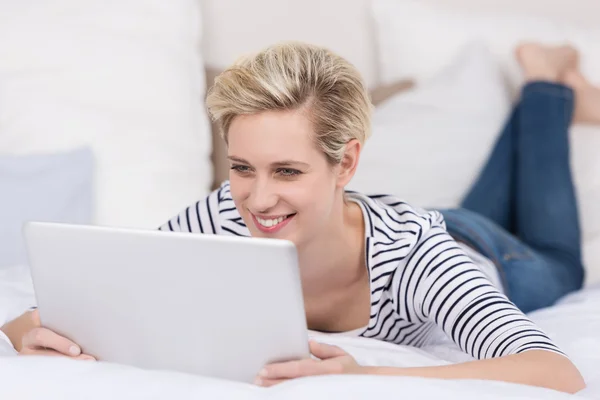 Mulher sorrindo enquanto lê seu tablet — Fotografia de Stock