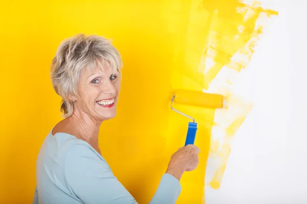Mulher sênior competente pintando uma parede — Fotografia de Stock